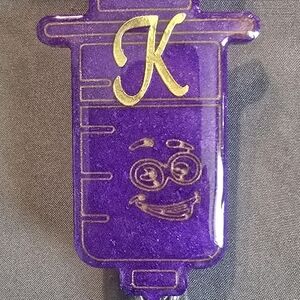 Purple Syringe-Shaped Badge Reel with Gold Letter K
